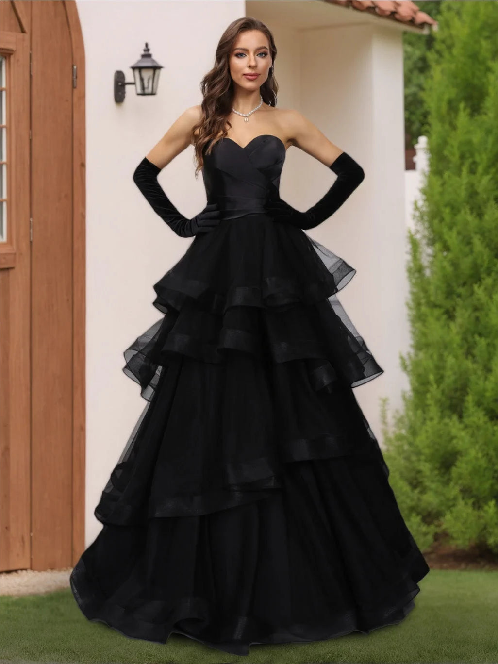 Black sweetheart A-line satin wedding dress with tiered ruffle skirt; hands on waist