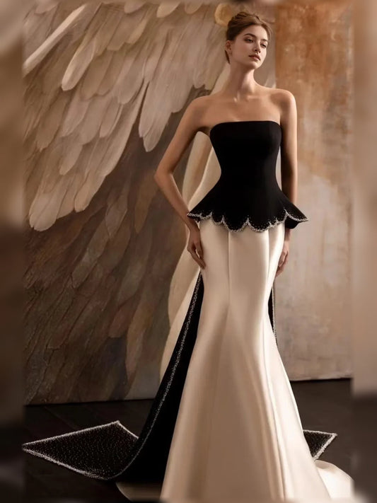 Strapless mermaid formal dress with black bodice, scalloped peplum, ivory champagne skirt.