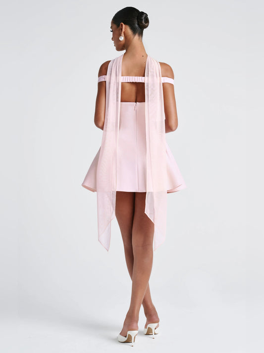 Blush mini dress back view: open back with sheer straps and layered chiffon drape, flared A-line skirt.