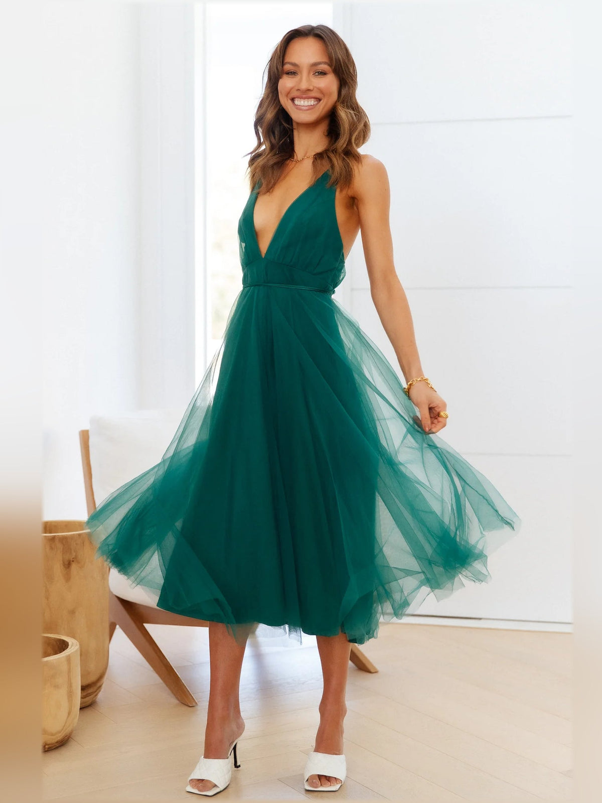 Forest green midi formal dress walking pose with V halter neckline and tulle skirt