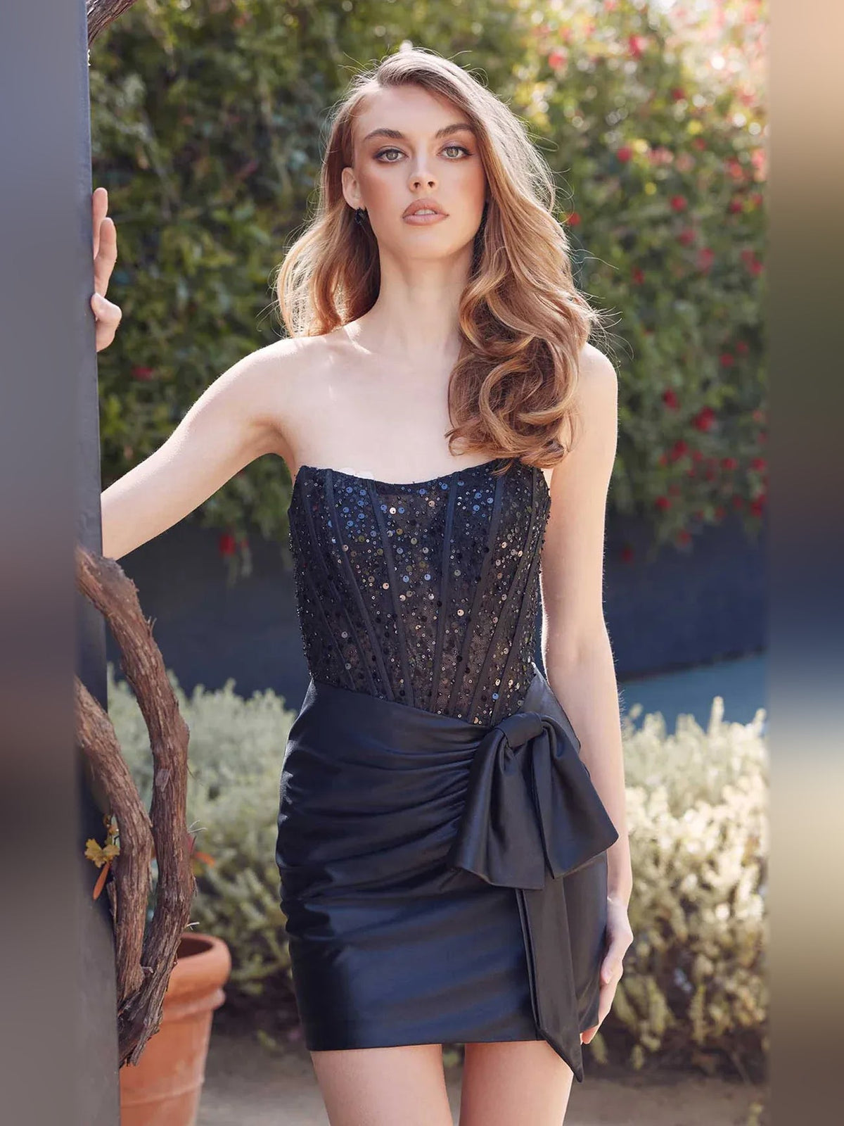 Dark satin strapless mini dress with ruched drape and bow detail at waist