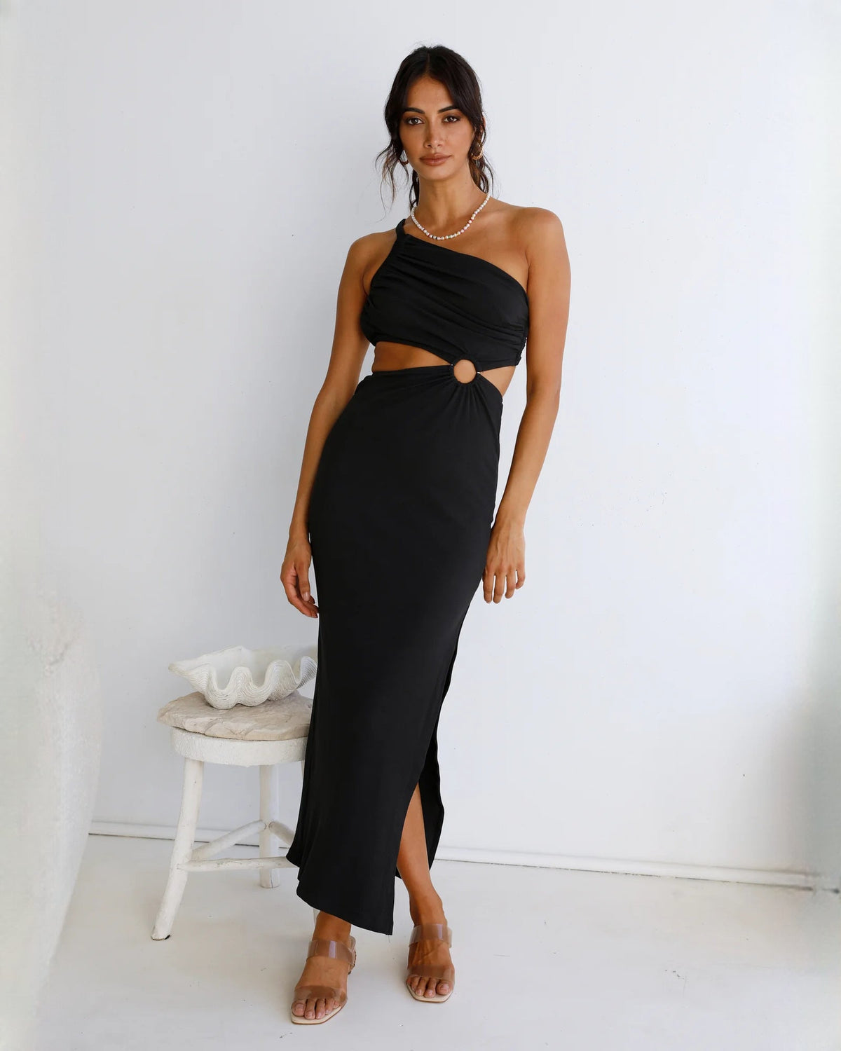 Black one-shoulder sleeveless maxi dress with draped waist, oval cutout, and side slit
