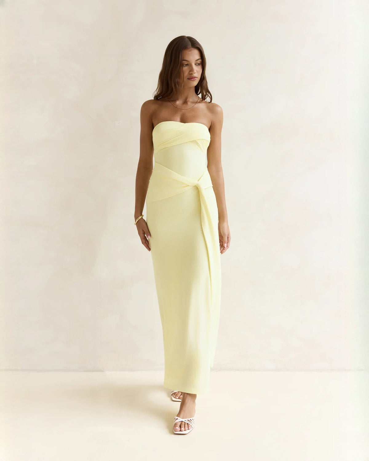 Light yellow strapless satin A-line maxi dress with wrap-front drape and long skirt