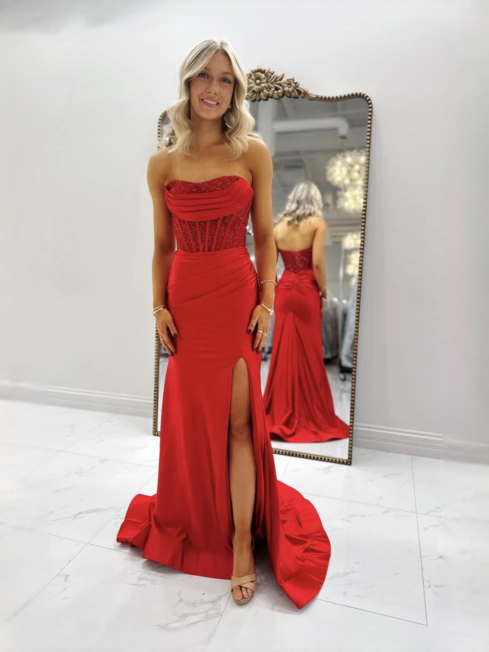 Red strapless satin prom dress with corset bodice, ruched details, and long slit