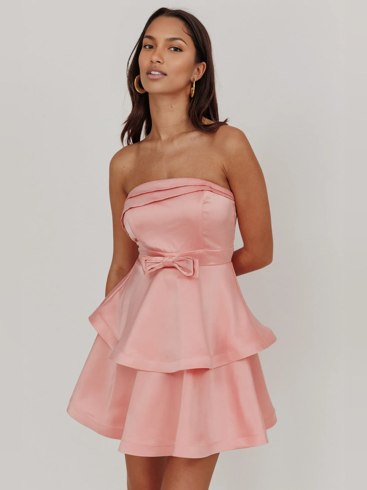 Pink strapless satin mini dress with tiered ruffled skirt and centered waist bow